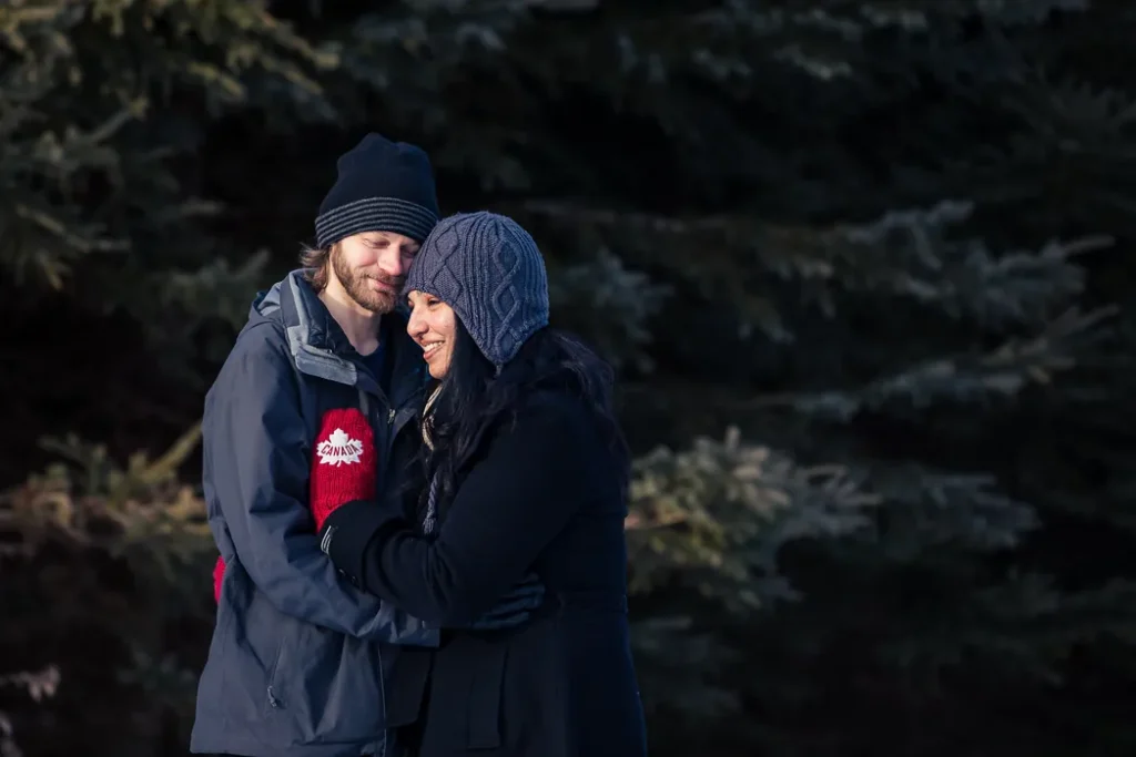 winter portrait of couple at lynde shores in front of evergreen trees.