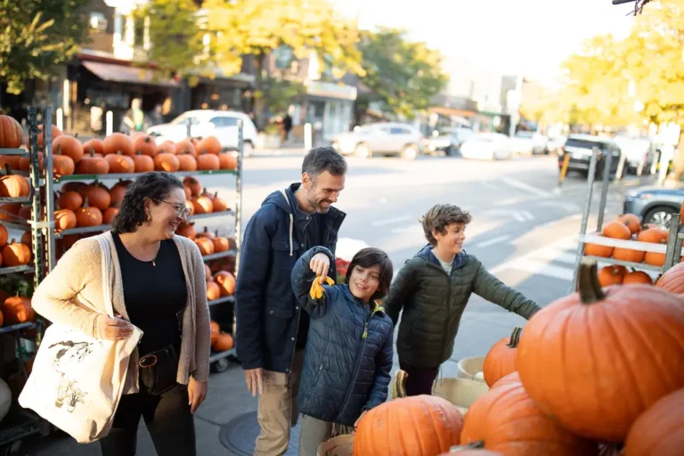 Candid fall family photo of kids choosing pumpkins on the Danforth in East York