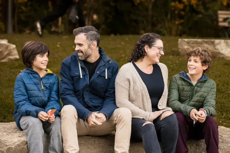 Family smiling together in Monarch Park during a fall photo session in East York
