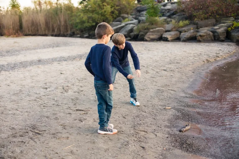 Two young boys skipping stones along the shoreline at Scarborough Bluffs during a fall family photo session