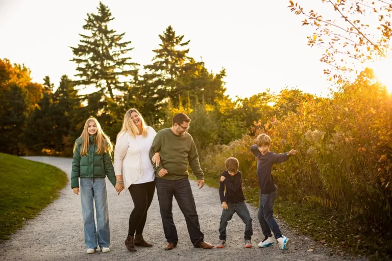 Family walking along a trail at Scarborough Bluffs during golden hour, laughing as the boys dance and play in the autumn light