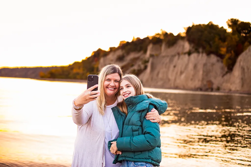 Mother and daughter taking a selfie together at the beach during a fall family photography session at Scarborough Bluffs