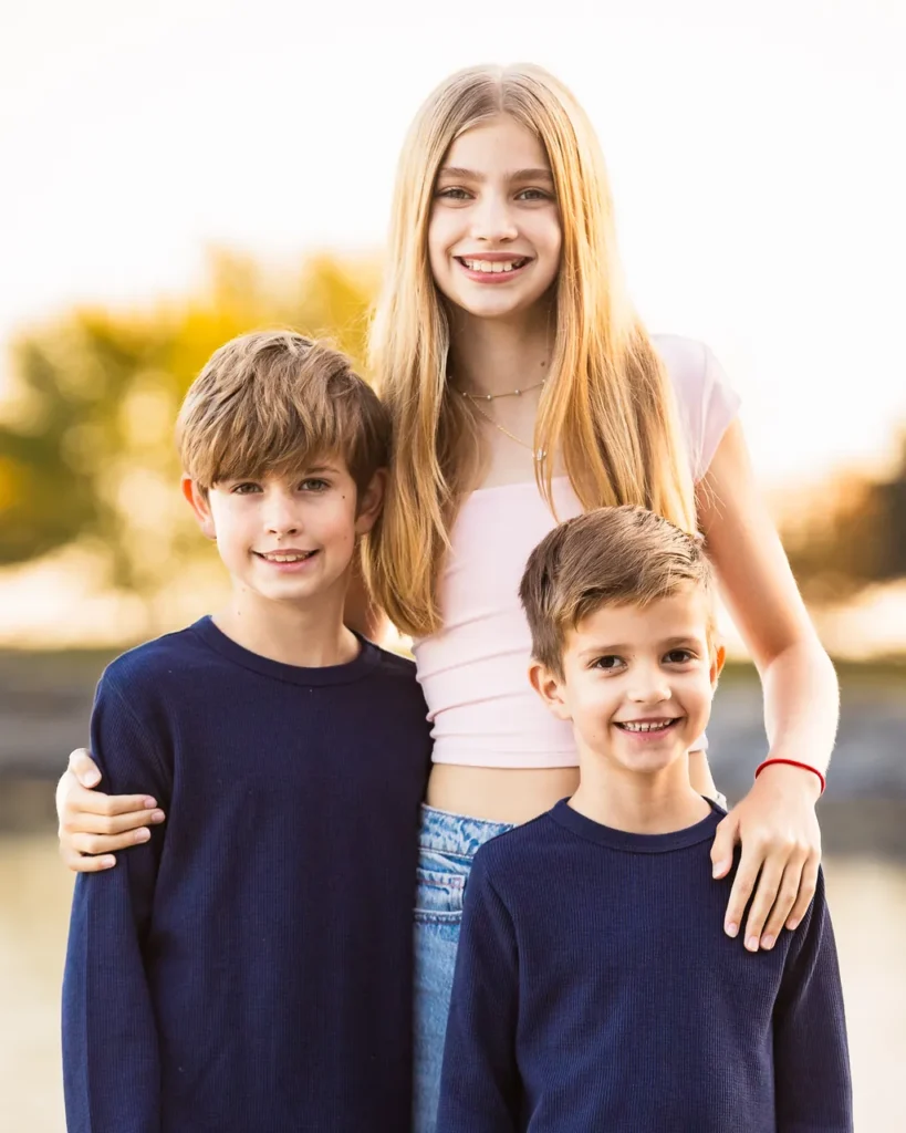 Three siblings sitting on rocks at Scarborough Bluffs beach during a fall family photo session