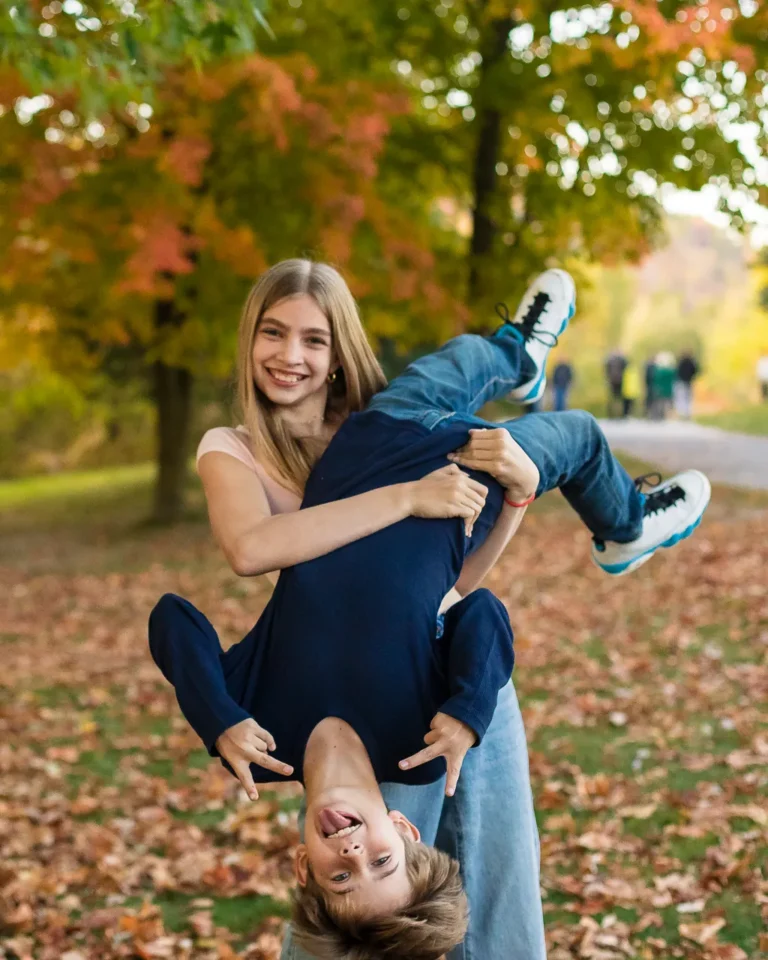 Big sister flipping her younger brother upside down in a candid fall moment at Scarborough Bluffs