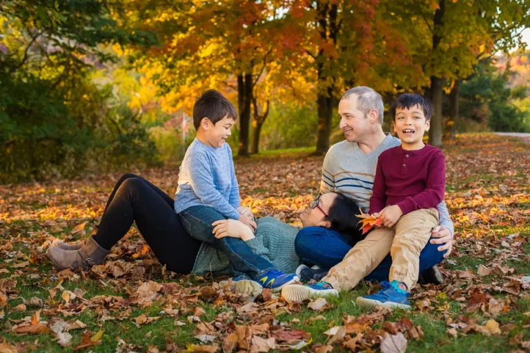 Family photo in fall sitting in the leaves